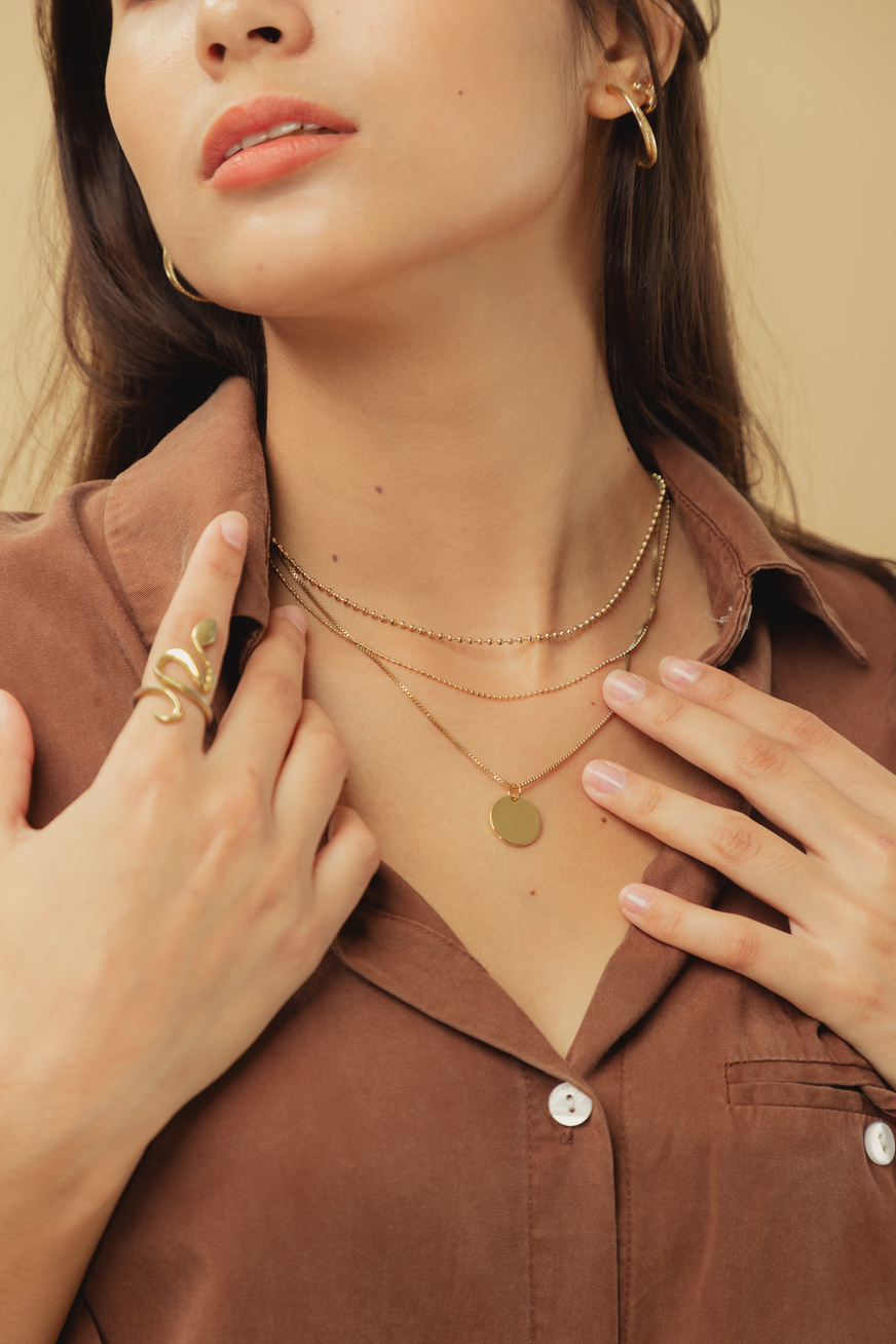 Woman in Brown Dress Shirt with Jewelry on Beige Background